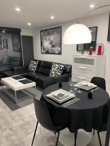 a living room with a black table and a black couch at Charmant studio neuf de 40m2 / tout confort in Arques-la-Bataille