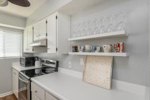 a kitchen with white cabinets and a white counter top at Shore to Please in Tybee Island