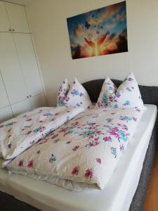 a bed with white sheets and pink flowers on it at Lebensfreude Appartement in Bad Goisern