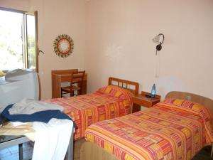 レッジョ・ディ・カラブリアにあるB&B La Pinetaのベッド2台、テーブル、窓が備わる客室です。