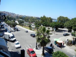 レッジョ・ディ・カラブリアにあるB&B La Pinetaの車とヤシの木が並ぶ賑やかな街道
