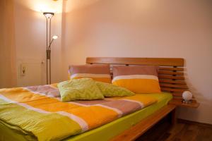 Schlafzimmer mit einem Bett mit bunter Bettwäsche und Kissen in der Unterkunft FEWO Wonta am Ossiachersee in Sattendorf