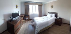 Habitación de hotel con cama grande y TV en Hotel El Conquistador en Cuenca