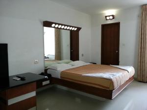 een slaapkamer met een bed, een tafel en een spiegel bij Lotus Bay View Hotel in Pondicherry