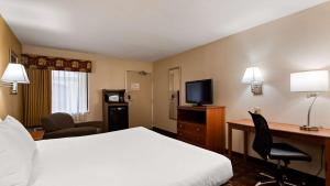 Habitación de hotel con cama, escritorio y TV. en SureStay Hotel by Best Western East Brunswick, en East Brunswick