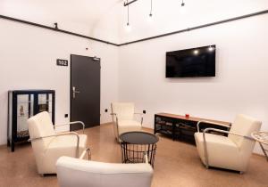 a living room with white chairs and a flat screen tv at AdHoc Hostel in Ljubljana