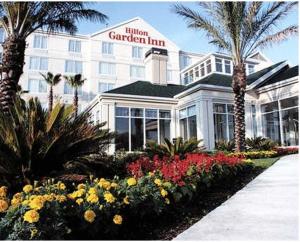 a hotel with palm trees and flowers in front of it at Hilton Garden Inn New Braunfels in New Braunfels