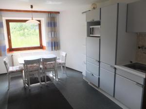 eine Küche mit einem Tisch und Stühlen sowie einem Fenster in der Unterkunft Bauernhaus Ramona in Holzgau