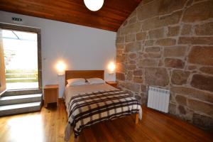 a bedroom with a bed and a stone wall at Casa de Santa Cristina in Alpendurada +10 photos