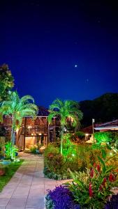 a garden at night with palm trees and lights at Pousada Meu Sossego in Barra Grande