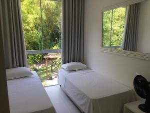 duas camas num quarto com duas janelas em Tangerina Hostel em Florianópolis