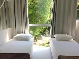 Duas camas num quarto com uma janela grande em Tangerina Hostel em Florianópolis