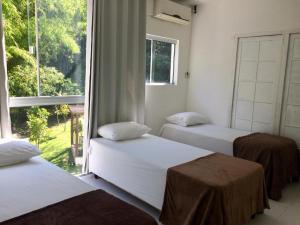 Três camas num quarto com uma grande janela em Tangerina Hostel em Florianópolis