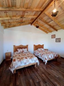 two beds in a room with wooden ceilings and wooden floors at Cabañas el Corral del Rayo Huasca in Huasca de Ocampo