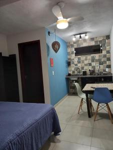 a bedroom with a bed and a table and a kitchen at Guest House Ilha do Mel in Ilha do Mel