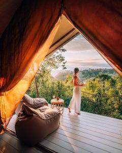 a woman standing inside of a tent with a view at Autentik Penida "Glamping" - Adults only in Nusa Penida