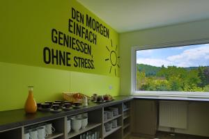 a kitchen with a green wall with a window at Smart Motel in Gars am Kamp