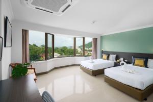 I Pavilion Hotel Phuket - SHA Extra Plus في فوكيت تاون: غرفة فندقية بسريرين ونافذة كبيرة
