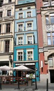 a blue building on a city street with tables at Academus - Cafe/Pub & Guest House in Wrocław