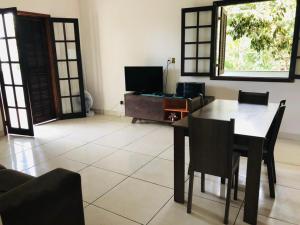 ein Wohnzimmer mit einem Tisch, Stühlen und einem TV in der Unterkunft Casa Mar e Montanha 1 in Trindade