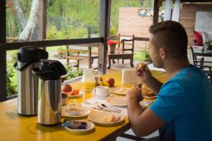 a young boy sitting at a table eating breakfast at Pousada Gata Russa in Saco do Ceu