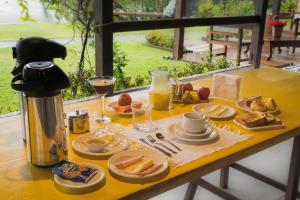 a table with a plate of food and glasses of orange juice at Pousada Gata Russa in Saco do Ceu