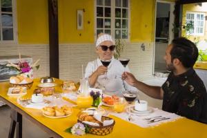 two people sitting at a table with a glass of wine at Pousada Gata Russa in Saco do Ceu