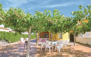 a patio with tables and chairs under an orange tree at Nice Home In Miami Playa With 3 Bedrooms in Miami Platja