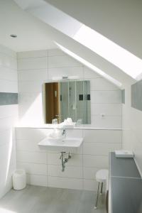 a white bathroom with a sink and a mirror at Gästehäuser Kappelmühle in Grünstadt