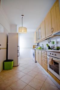 uma cozinha com armários de madeira e um frigorífico branco em Dalia em Quarteira