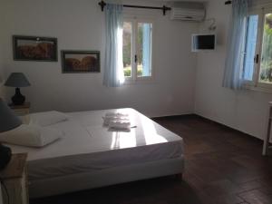 a bedroom with a white bed and two windows at Antigoni in Skiros