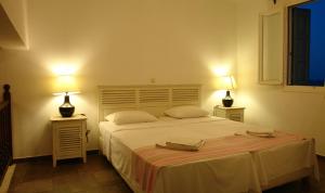 a bedroom with a large white bed with two lamps at Antigoni in Skiros +20 photos