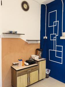 a kitchen with a counter and a blue wall at Travellers Diary Guesthouse in Melaka