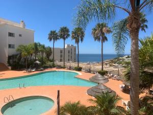 een zwembad met palmbomen en de oceaan bij Lagos Beach 59A in Lagos