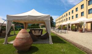 tenda bianca con tavolo e sedie di fronte a un edificio di Hotel Barrage a Pinerolo