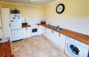 a kitchen with white cabinets and a sink and a clock at 2 Bedroom Awesome Home In Chelun in Chelun