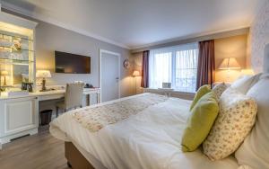 Schlafzimmer mit einem großen weißen Bett und einem Schreibtisch in der Unterkunft Ara Dune Hotel in De Panne