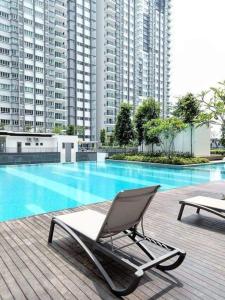 a lounge chair next to a swimming pool with tall buildings at Cikta Homestay at Southville City Savanna Suite in Kampong Tangkas