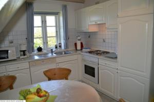 - une cuisine avec des placards blancs et un bol de fruits sur une table dans l'établissement Luv - a05408, à Dunsum