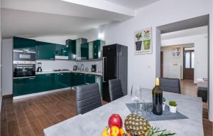 eine Küche mit grünen Schränken und einem Tisch mit Obst darauf in der Unterkunft Beautiful Home In Loborika With Kitchen in Loborika