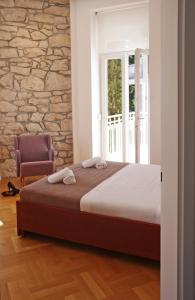 1 dormitorio con cama, silla y pared de piedra en Guest House Villa Dagmar en Crikvenica