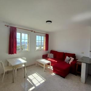 a living room with a red couch and a table at Apartamentos Las Canteras Arena in Las Palmas de Gran Canaria