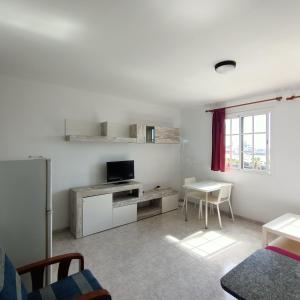 sala de estar con TV y mesa en Apartamentos Las Canteras Arena, en Las Palmas de Gran Canaria