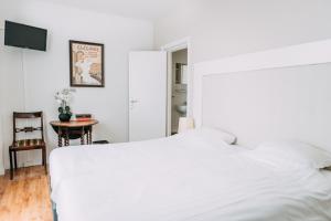 um quarto com uma cama branca e uma mesa em Hotel Café Restaurant Abina em Amstelveen