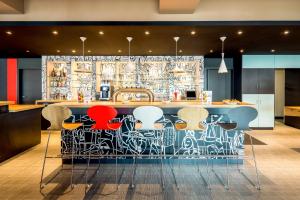 a kitchen with a bar with colorful stools at ibis Hotel München Garching in Garching bei München