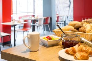 a table with a tray of bread and a plate of food at ibis Hotel München Garching in Garching bei München