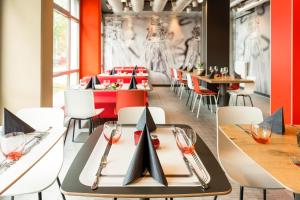 a restaurant with orange walls and tables and chairs at ibis Hotel München Garching in Garching bei München