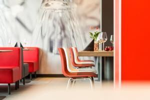 a dining room with red chairs and a table at ibis Hotel München Garching in Garching bei München