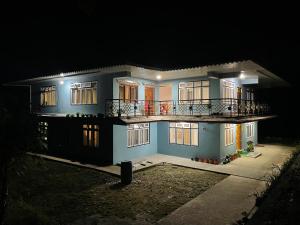 ein großes blaues Haus mit Balkon in der Nacht in der Unterkunft KHIMSHA HOMESTAY in Pelling