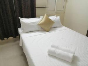 uma cama branca com lençóis e almofadas brancos em Aarudhara Holiday Home (A Home away from Home) em Pondicherry